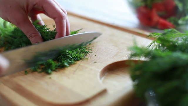 Woman cuts dill salad.