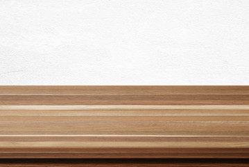 Empty wooden table over white cement wall background
