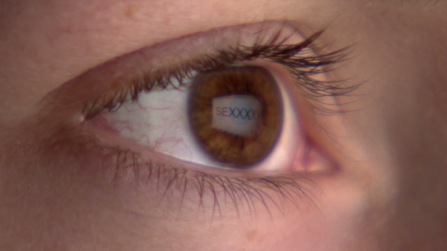 Eye watching the screen with the reflection of the word "sex"