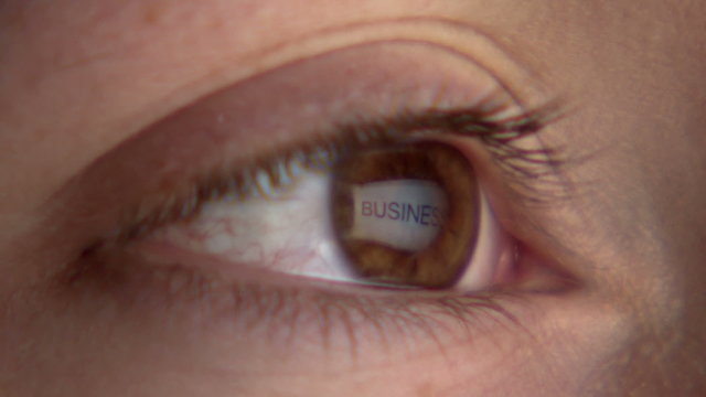 Eye watching the screen with reflection of the word "business"