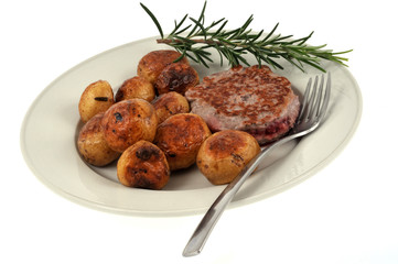Assiette avec un steak haché, des pommes de terre grenailles et un brin de romarin