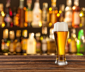 Glass of light beer with bar on background