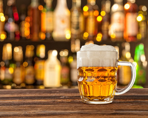 Glass of light beer with bar on background