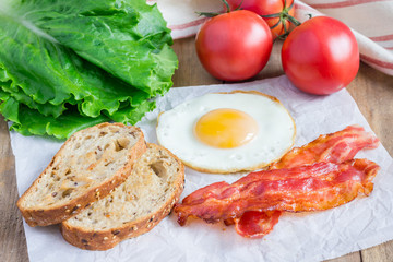 Making open face sandwich with egg, bacon, tomato and lettuce
