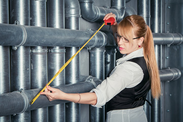 Attractive businesswoman measuring distance between plastic pipes in PVC pipes construction using...