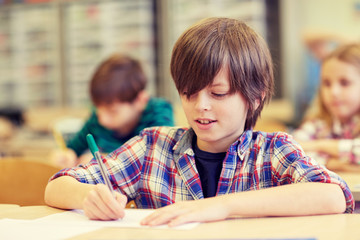 group of school kids writing test in classroom