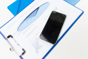 close up of smartphone and clipboard with charts