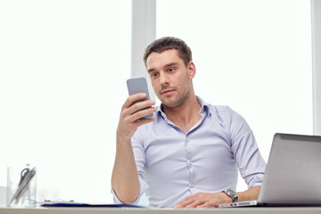 businessman with smartphone and laptop at office