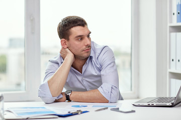 bored businessman with laptop and papers at office