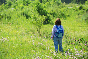 Rear view of mature woman on bright green grass background.