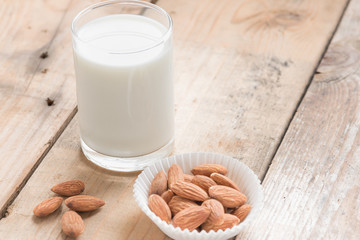 Almond milk with almond on a wood table.