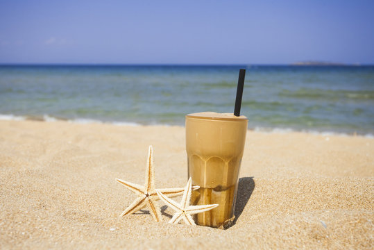 Iced coffee on a sandy beach background
