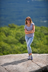 Young woman posing at the edge of rock at Minnewaska State Park Reserve Upstate NY during summer time