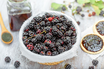 Bowl of fresh blackberries and cookies with jam on table