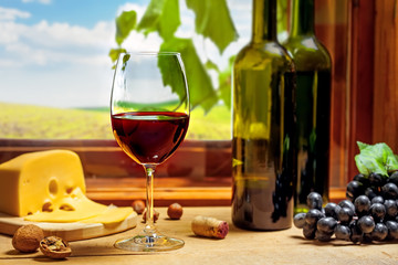 Wine in a bottle and glass with cheese, grape and nuts on table