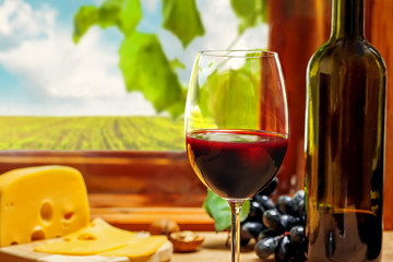 Wine in a bottle and glass with cheese, grape and nuts on table