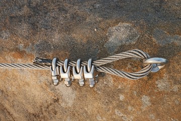 Solid knot on steel rope. Iron twisted rope fixed in block by screws snap hooks. Detail of rope end...