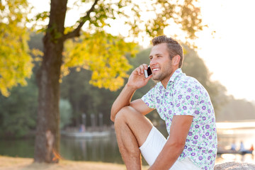 Fototapeta premium Portrait of a young man in a city park on a sunset