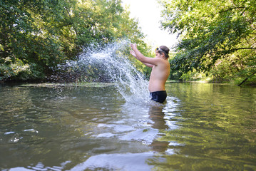 Boy teenager swims in  river in summer