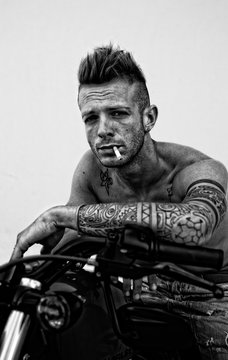 Young boy with tattoo Maori smoking on motorcycle
