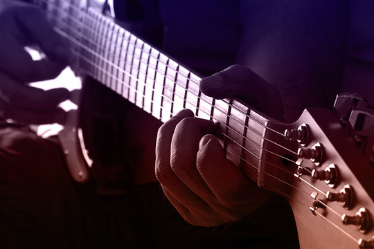 Playing guitar on purple and orange light