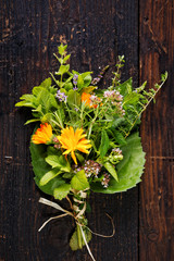 Bouquet of various fresh organic herbs on a wooden background