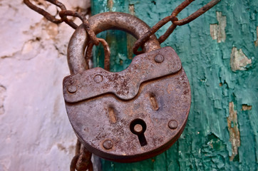 On the old wooden door, installed a rusty padlock