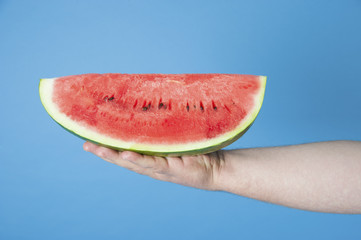 Large slice of watermelon on a man's hand..