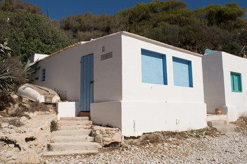 Obraz na płótnie Canvas White-washed Spanish beach huts on a pebbled beach