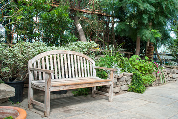 Wooden Bench in a Garden surrounded by evergreens and tropical p