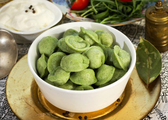 Russian cuisine. Pelmeni meat dumplings witn basil, ruccola and culinary plants, fresh farm cream and bay leaf