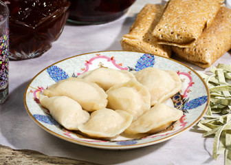 Russian cuisine. Pelmeni meat dumplings with meat stuffed pancakes and homemade noodles on a vintage crockery