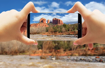 Smartphone taking photo of Cathedral Red Rocks Mountain in Sedona with stream and trees