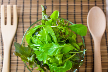 Fresh vegetable salad with green oak and rocket with wooden spoon and fork. (Shallow aperture intended for  the aesthetic quality of the blur.)