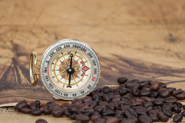 Vintage compass and bean lies on an ancient map