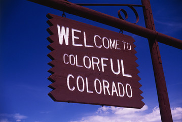 This is a road sign that says, Welcome to Colorful Colorado. It is a brown wood sign, painted with white letters against a blue sky.