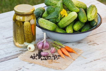 Cucumbers in metal bowl, vegetables and spices for pickling and jar pickled cucumbers