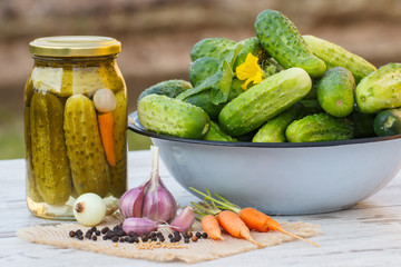 Cucumbers in metal bowl, vegetables and spices for pickling and jar pickled cucumbers