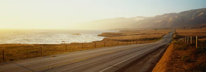  Dit is Route 1 ook wel bekend als de Pacific Coast Highway. De weg ligt naast de oceaan met de bergen in de verte. De weg gaat in het oneindige de zonsondergang in. © spiritofamerica