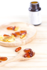 Closeup soft gelatin supplement fish oil capsule on wooden