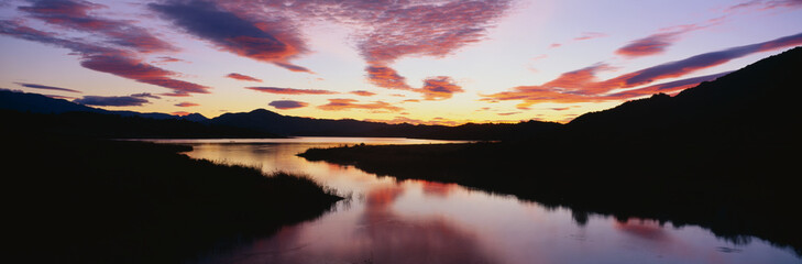 This is Lake Casitas at sunrise. There is a pinkish glow from the sun reflected in the lake.