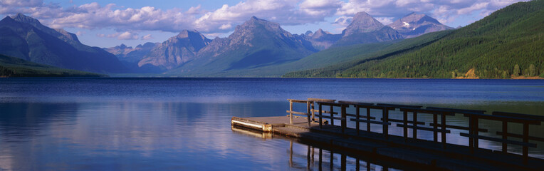 This is a boat dock at Lake McDonald. The blue water of the lake surrounds the dock with mountains...