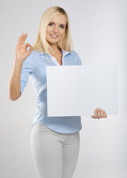 young woman with blank sign board and showing okay gesture