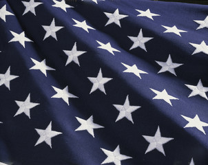 Obraz na płótnie Canvas These are the stars of the American flag. They are against their blue field, climbing upward toward the corner of the image as if they were situated on small stairs that move up in levels..