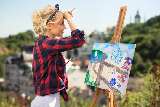 Beautiful blonde woman artist paints a colorful picture.
