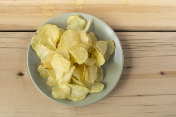 Some potato chips on a green plate on a wooden table