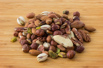Close-up of mixture of several different peanuts on a wooden table.