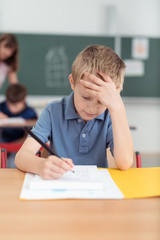 schulkind grübelt über einer aufgabe