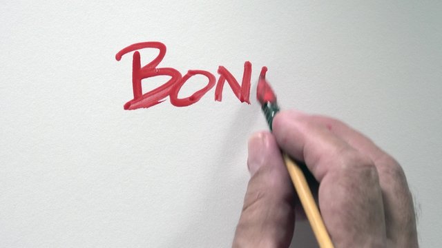 Human hand writing word "BONNE ANNEE" in french, with red gouache