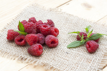 Fresh sweet red raspberry and mint on light wooden table, selective focus
